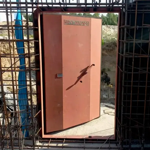 Vue de la face intérieure d'une porte de bunker para-souffle 4.4 bar et étanche aux gaz, ouverte, avec ferraillage et avec apprêt anti-corrosion de couleur rouille.